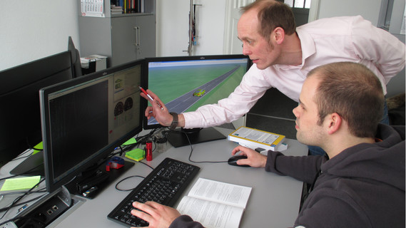Das Bild zeigt Prof. Dr.-Ing. Reiner Kriesten und einen Studierenden vor einem Computermonitor bei der Analyse der modellbasierten Reichweitensimulation.