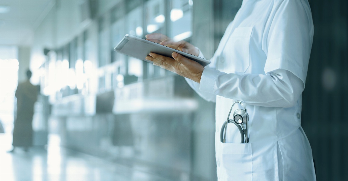 Ärztin die mit Tablet in der Hand auf Krankenhausflur steht