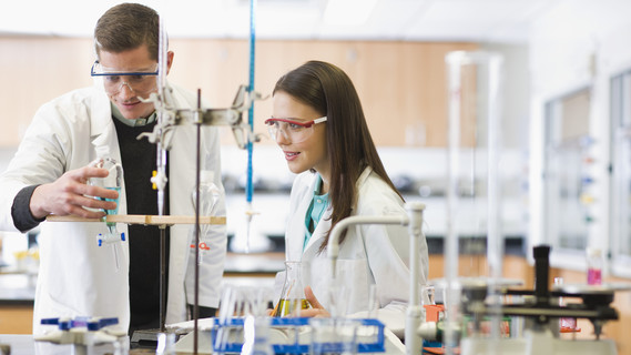 Ein Dozent demonstriert einer Studentin ein Experiment