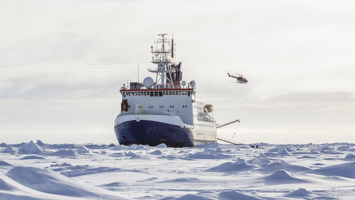 Forschungsschiff und Hubschrauber zwischen Eisschollen im Polarmeer