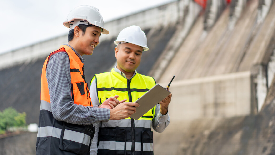 Ingenieure stehen vor einer Wasserkraftanlage