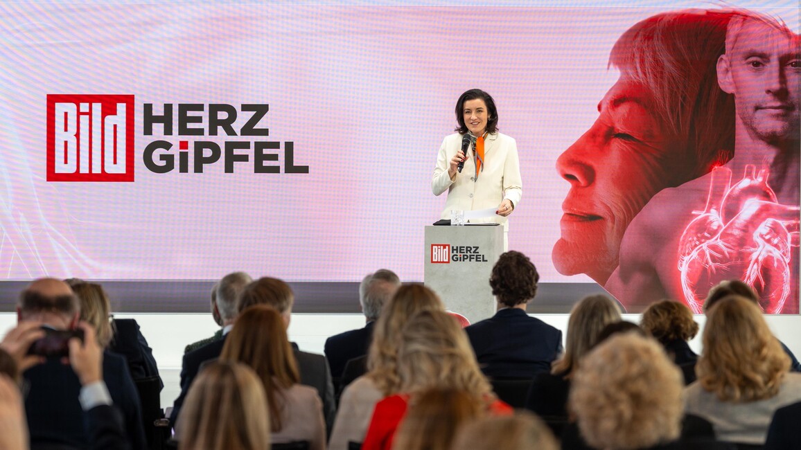 Bär steht auf einem Podium und spricht