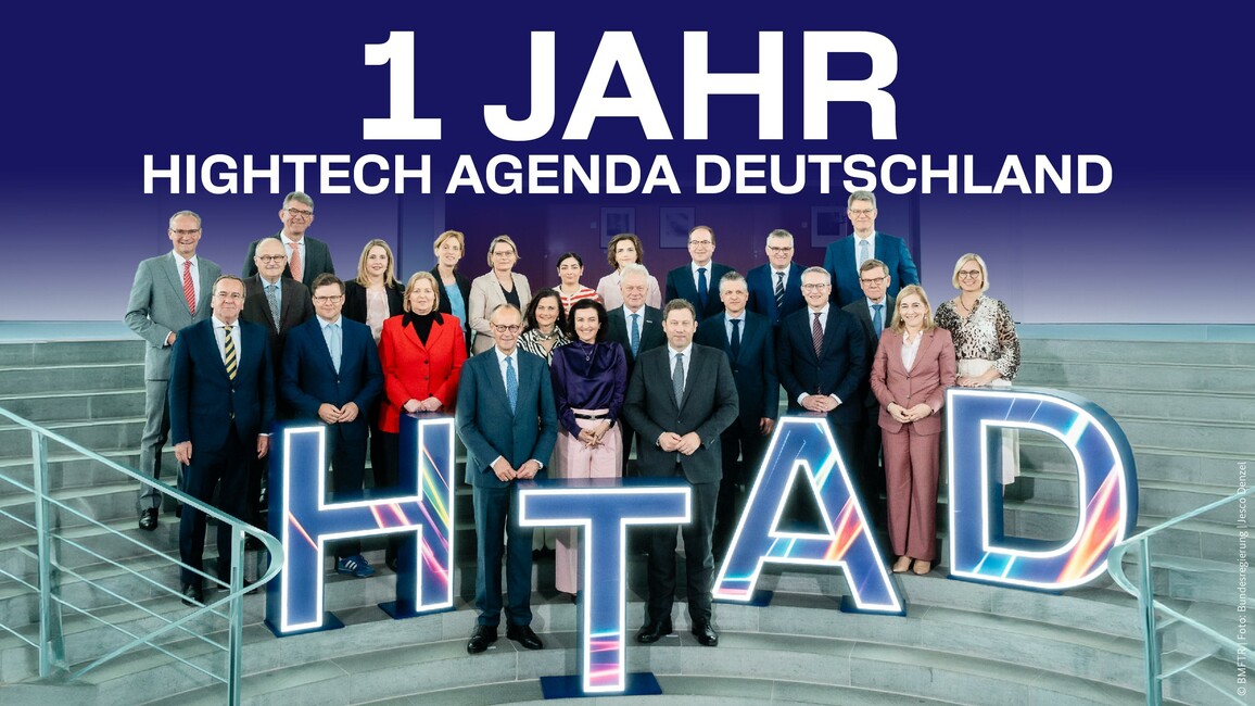 Die Bundesminister und -ministerinnen sowie der Bundeskanzler Merz posieren vor der HTAD. Text: 1 Jahr Hightech Agenda Deutschland.
